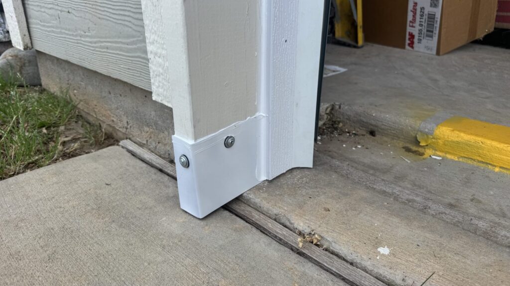 The sealed garage door corner from inside the garage, with the metal shaped to follow the slope of the slab.